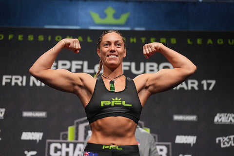 Woman flexing her muscles in front of a branded backdrop